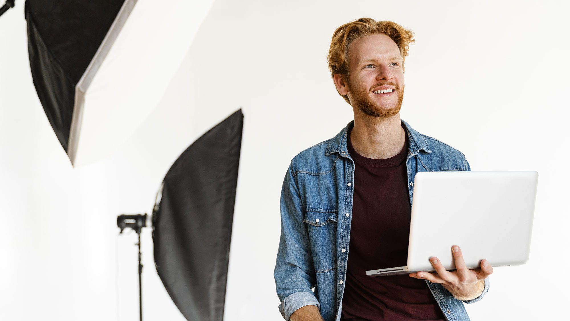 lächelnder fotograf mit laptop im fotostudio